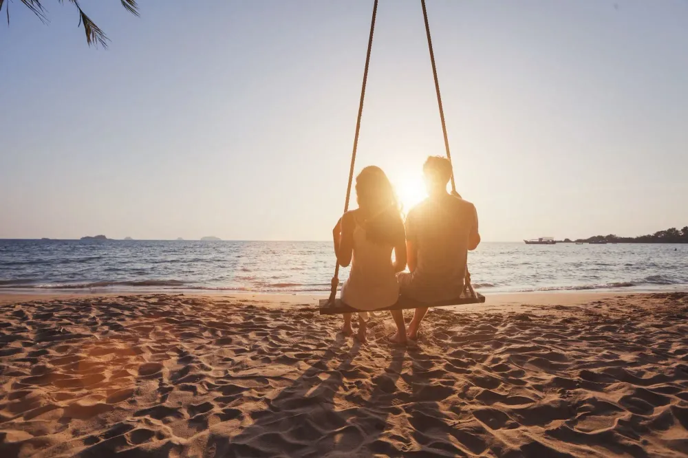 Silhouette of couple on swing on beach